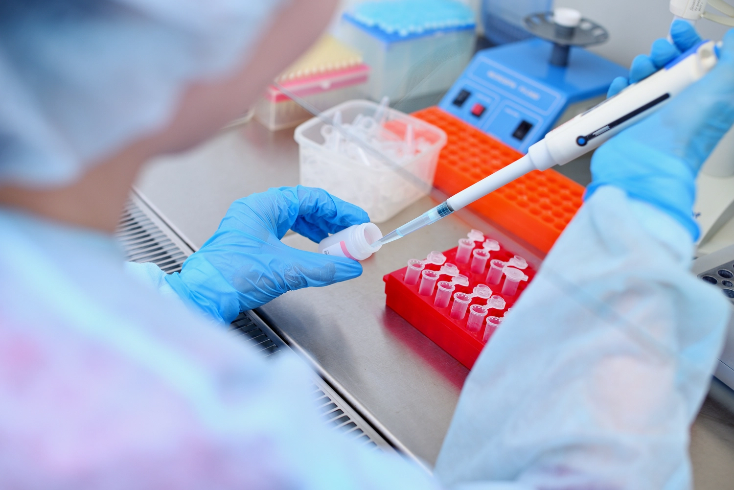 PCR-Test – Reagenzienhersteller – DNA-Test im Labor. Ein Labortechniker führt mit einem Dispenser in der Hand eine DNA-Analyse in einem sterilen Labor hinter Glas durch.