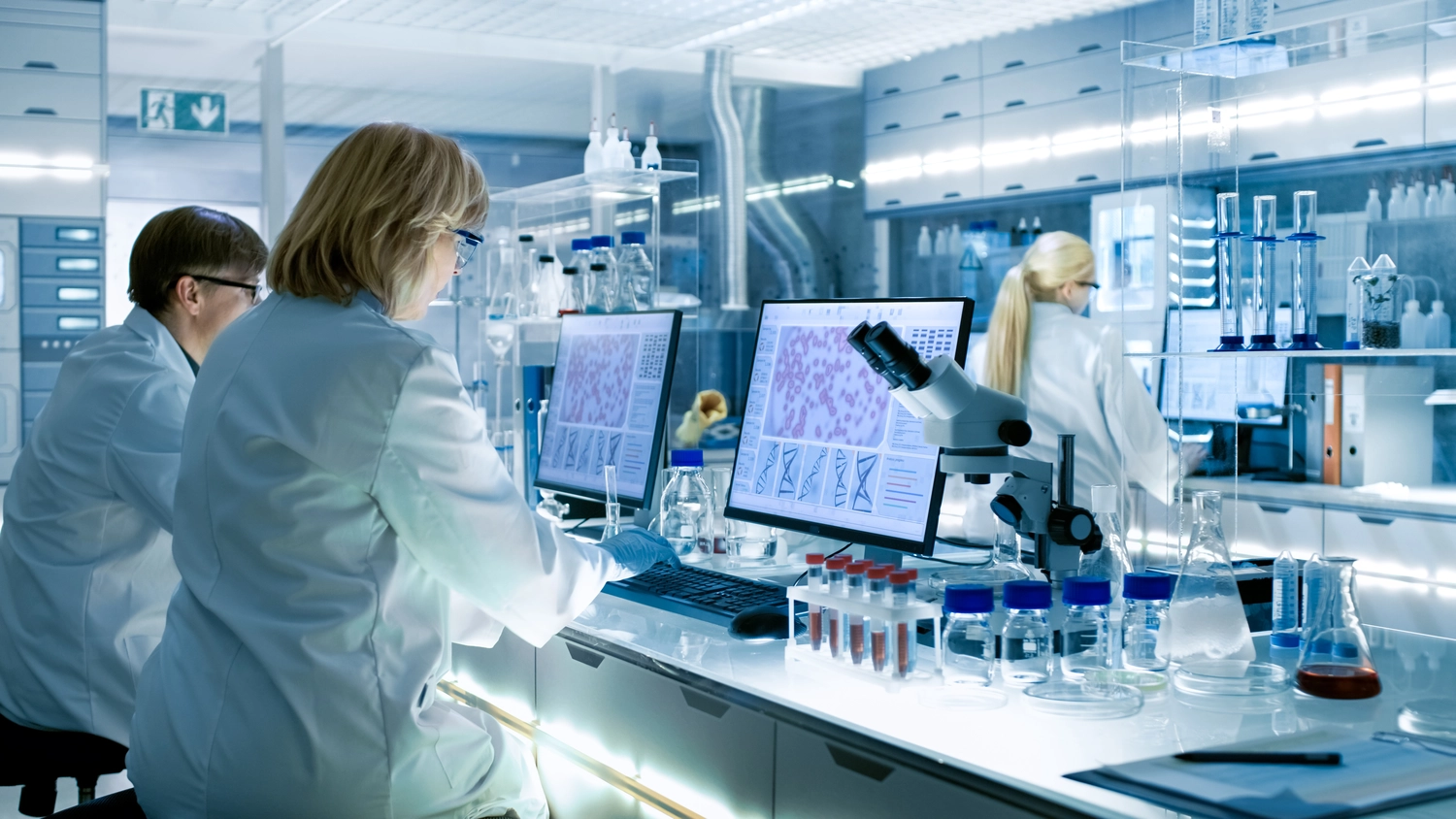 PCR-Test - PCR-Testverfahren - Wissenschaftlerinnen und Wissenschaftler arbeiten an ihren Computern im großen modernen Labor.